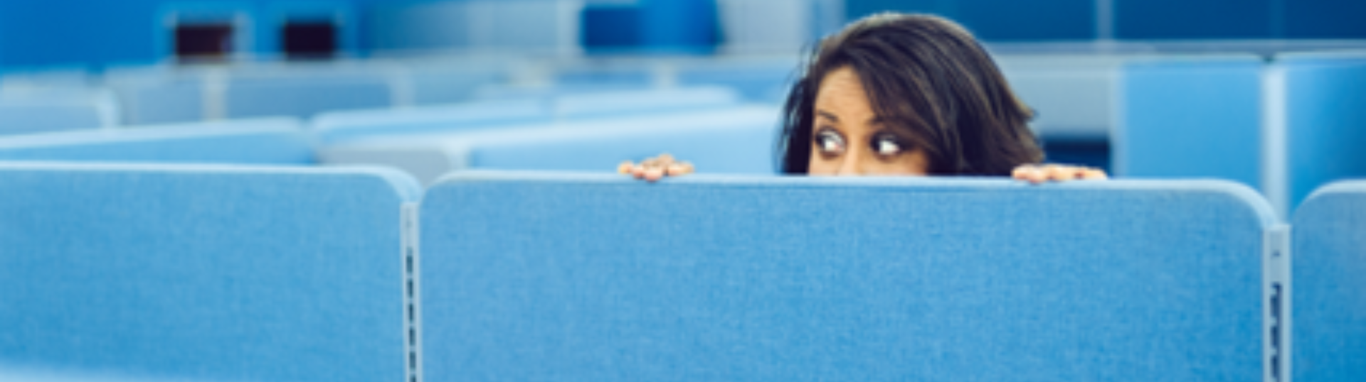 A woman hidden in an office cubicle